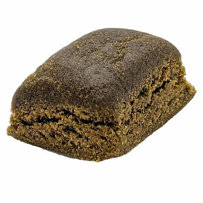 Dense brick of pressed brown hash with a crumbly broken edge.
