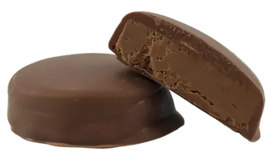 Two round chocolate-coated bites, one whole and one halved showing a soft hazelnut filling inside