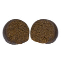 Two round balls of Animal Face Temple Ball hash sliced open, showing a dense, crumbly dark brown interior.