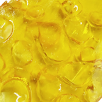 Close-up macro view of amber shatter concentrate showing its glassy, bubbled surface texture.