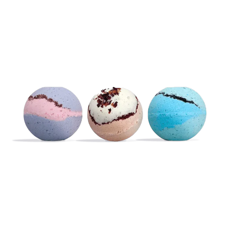 Three round bath bombs in a row: purple and pink swirl, cream with dark red flecks, and blue and teal swirl