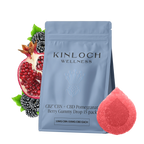 Blue stand-up pouch labeled Kinloch Wellness CBZ CBN + CBD Pomegranate Berry Gummy Drop 15 pack, beside a halved pomegranate, blackberries, and a red sugar-coated gummy.