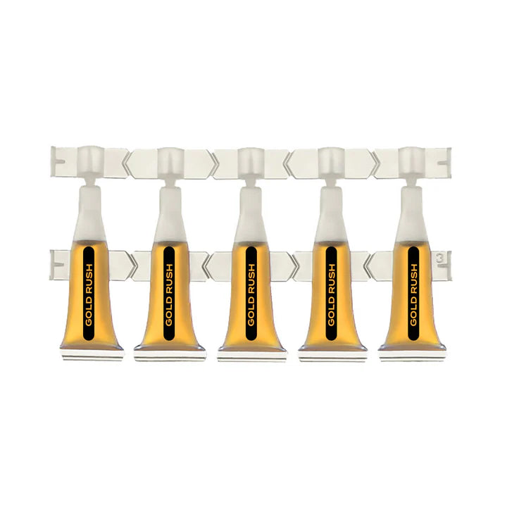 Five clear ampules of amber Gold Rush shatter oil connected on a perforated dosing strip.