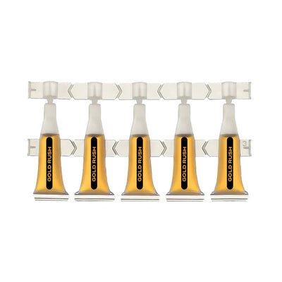 Five clear ampules of amber Gold Rush shatter oil connected on a perforated dosing strip.