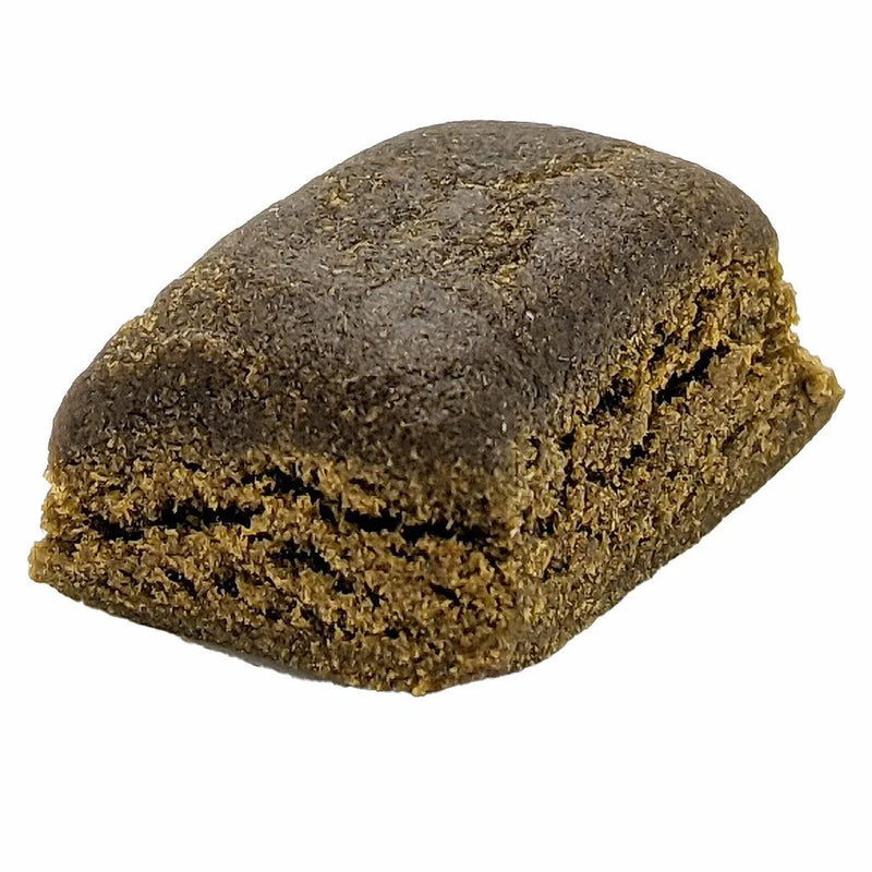Dense brick of pressed brown hash with a crumbly broken edge.
