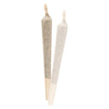Two cone-shaped pre-rolled joints with twisted tips standing upright, one on tan paper and one on white paper