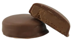 Two round chocolate-coated bites, one whole and one halved showing a soft hazelnut filling inside