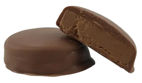 Two round chocolate-coated bites, one whole and one halved showing a soft hazelnut filling inside