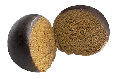 Two rounded pieces of pressed hash sliced open, showing a dark outer layer and granular olive-brown interior.