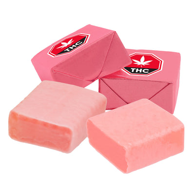 Four pink strawberry taffy candy pieces, two wrapped in foil printed with a THC symbol and two unwrapped.