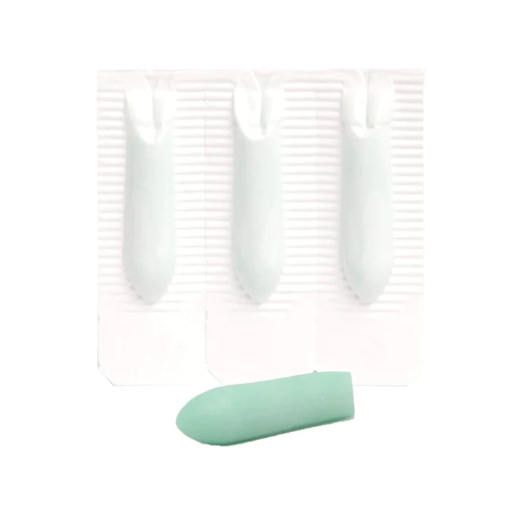 Close-up of three foil-backed suppositories on a blister strip next to one pale green suppository removed from its wrapper.