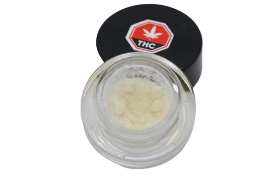 Open glass jar of pale yellow micronized THC isolate powder with its black THC-labeled lid resting beside it